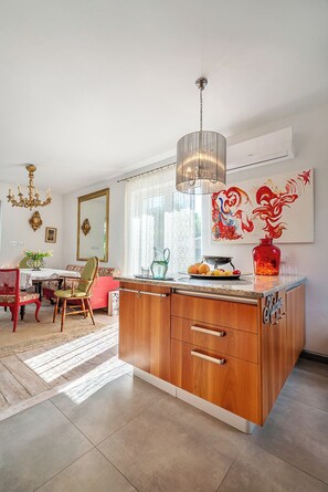 Una cucina moderna con isola in legno, un lampadario e un grande specchio.