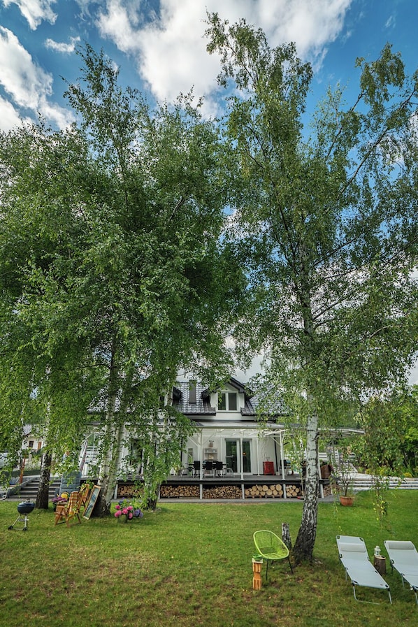 A house with a covered porch, a lawn, and a tree in the foreground.