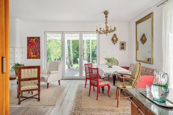 A dining area with a table, chairs, a chandelier, and a view through glass doors.