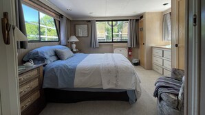 A bedroom with a bed, dresser, and a window with curtains. - 2-bedroom house boat in beautiful La Crosse with AC comfort (La Crosse)