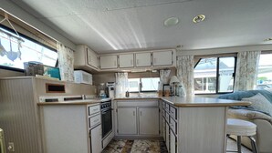 A compact RV kitchen with a stove, microwave, and sink. - 2-bedroom house boat in beautiful La Crosse with AC comfort (La Crosse)