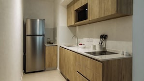 Una cocina moderna con armarios de madera, un refrigerador de acero inoxidable, un lavamanos y un microondas.