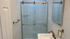 Un baño con ducha, inodoro, lavabo y espejo.