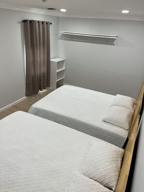 Une chambre avec deux lits, une armoire et une fenêtre avec des rideaux.