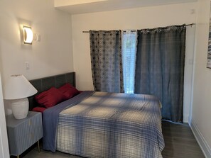 A bedroom with a bed, a bedside lamp, a nightstand, and a window with patterned curtains. - Perfect 3-bedroom apartment with AC in vibrant Toronto (Toronto)
