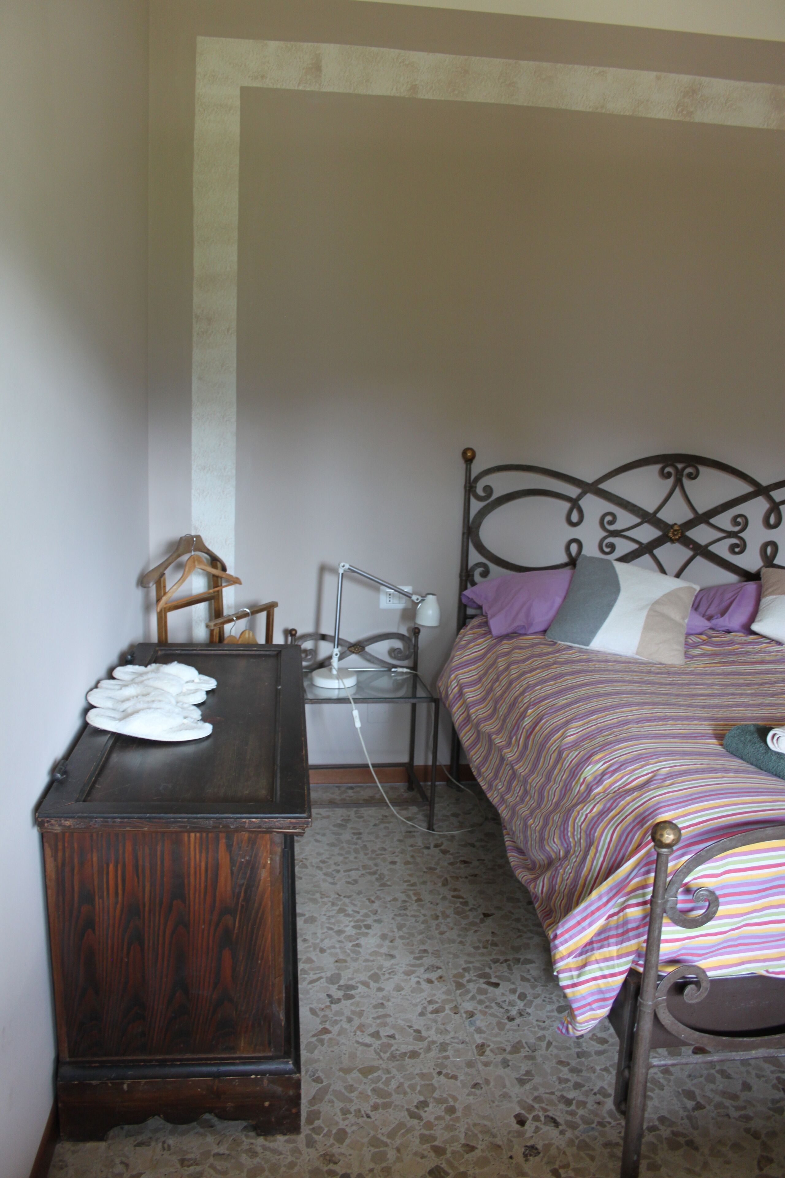 Een slaapkamer met een bed, een houten nachtkastje, een bureau en een stoel.