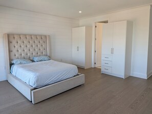 A bedroom with a large bed, a wardrobe, and a door.
