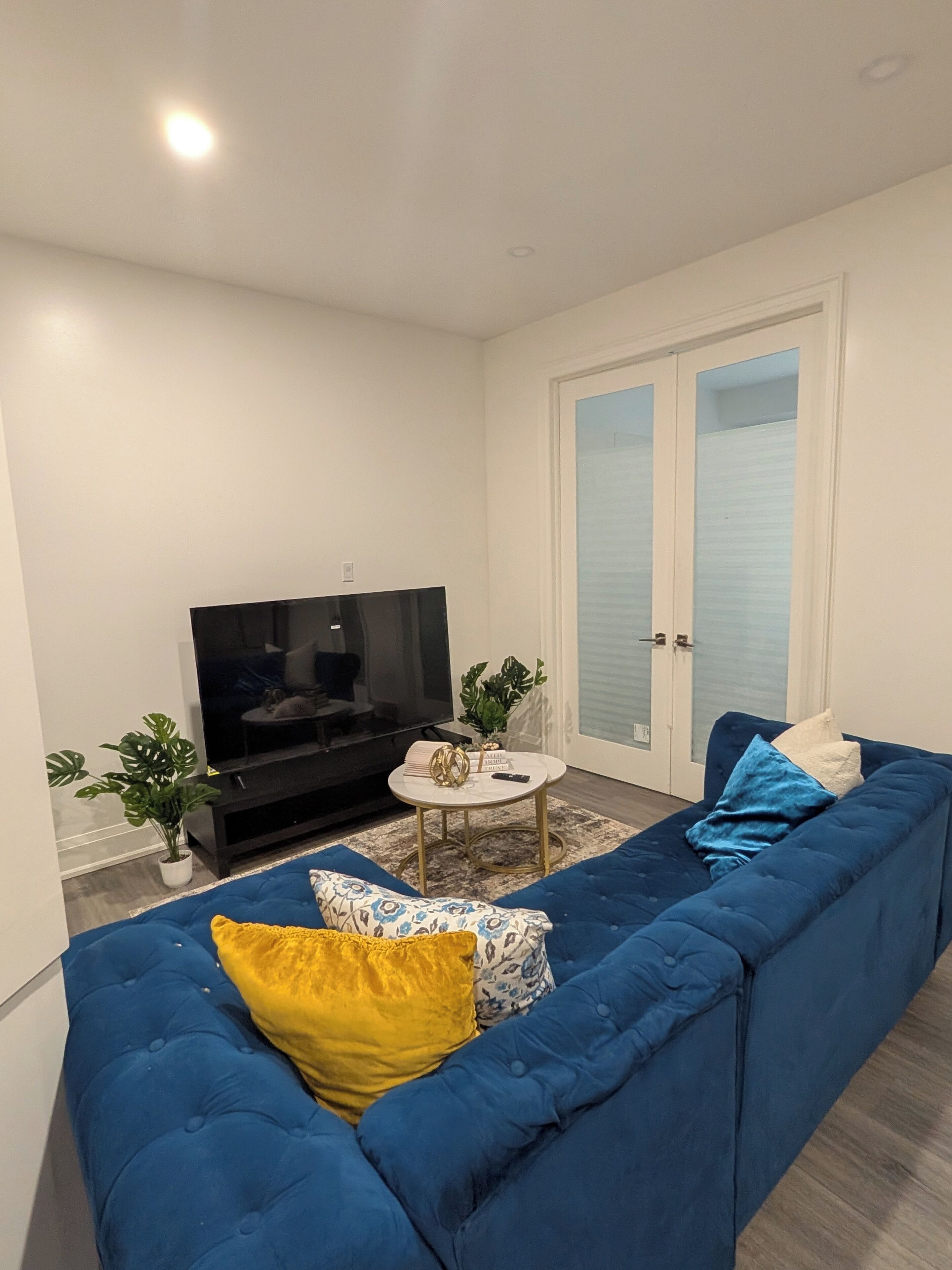 A living room with a blue sofa, a television, and a small round table with decorative items.