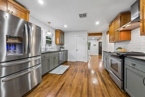 A modern kitchen with stainless steel appliances, wooden cabinets, and a hardwood floor. - Lake Austin Hideout - Walk to Downtown, Festivals, Ladybird Lake, and Zilker. (Austin)