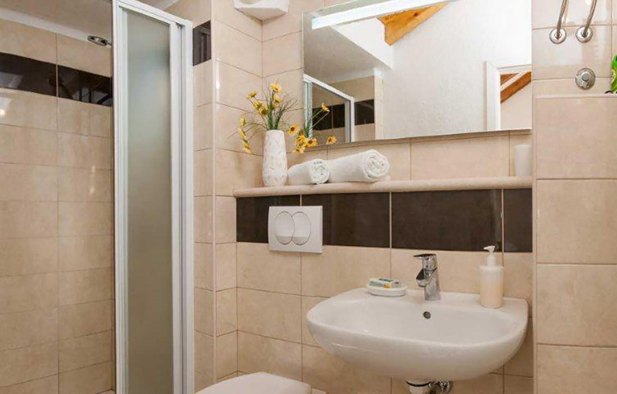 Un baño con lavabo, espejo, toallero y zona de ducha.