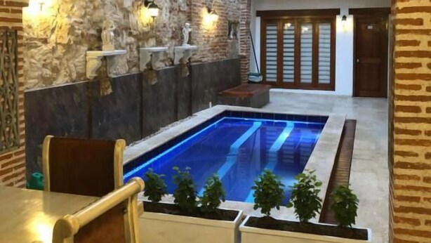 Una piscina interior con pared de piedra y cubierta de madera.