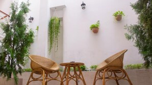 Un patio con mobiliario de mimbre, plantas en macetas e iluminación de pared.