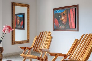 Ein Zimmer mit zwei Holzstühlen, einem großen Spiegel und zwei gerahmten Kunstwerken an der Wand.
