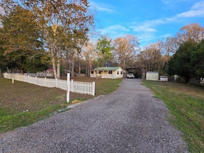 A gravel driveway leading to a covered structure with a vehicle parked inside.