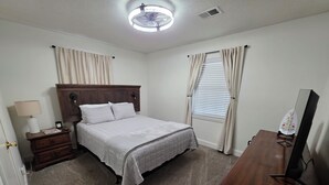 Un dormitorio con cama, mesita de noche, cómoda y ventilador de techo.