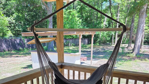 A wooden deck with a hanging hammock chair. - Padgett Peaceful Acres (Andalusia)