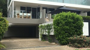 Een modern huis met twee verdiepingen, een overdekte buitenruimte, een garage en een verzorgde tuin.