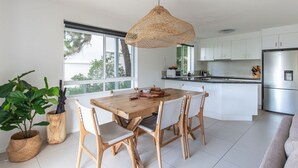 Een moderne keuken met witte kasten, een roestvrijstalen koelkast en een houten eettafel met stoelen.