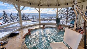 A hot tub with a view of snow-covered trees and mountains.