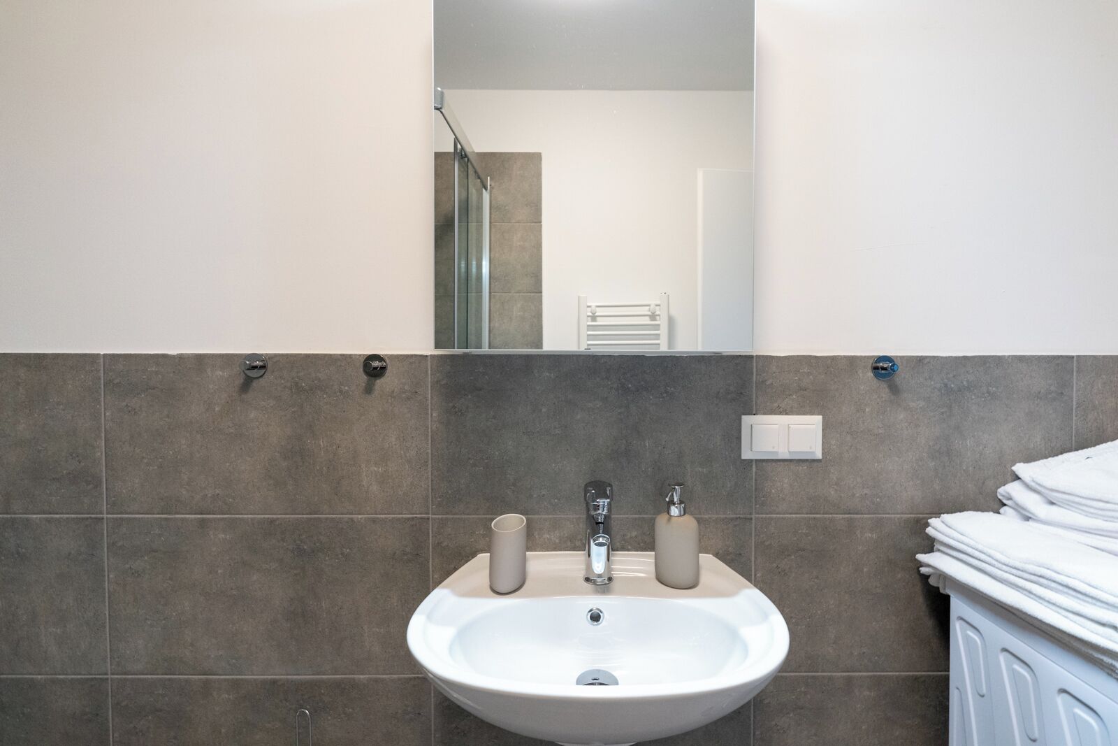 A bathroom with a sink, two faucets, a mirror, and a towel rack.