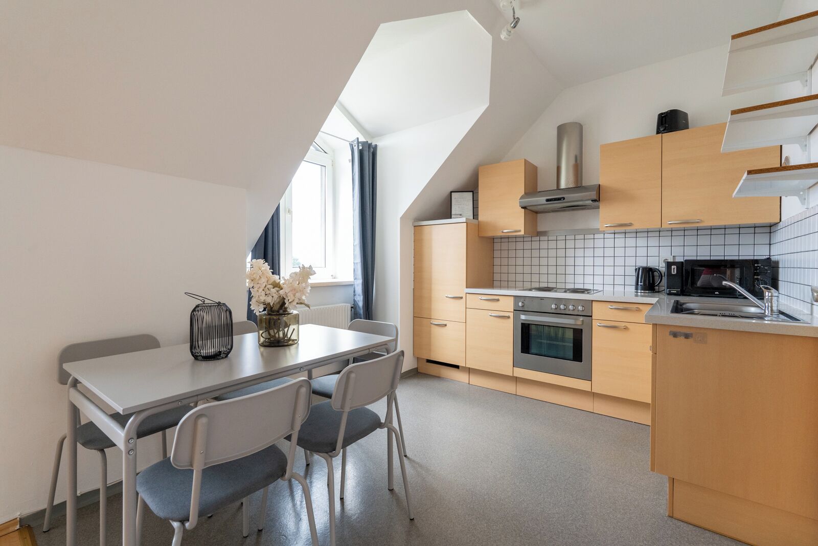 A modern kitchen with a dining area, featuring a stove, oven, microwave, and a small sink.