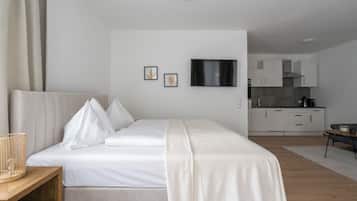 A bedroom with a bed, bedside table, and a view into the kitchen.