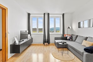 A modern living room with a sofa, TV, and a view of the outdoors.