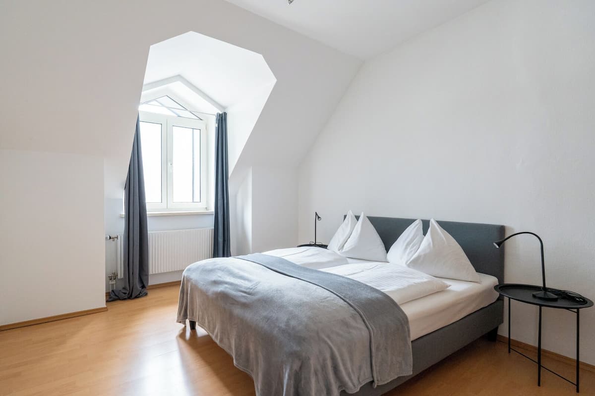 Une chambre à coucher avec un lit, une table de chevet, une fenêtre et un puits de lumière.