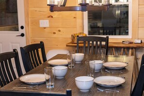 A dining table set with plates, bowls, glasses, and cutlery, with chairs around it. - 11m Killington & Okemo - New Cozy Ski Cabin / Rt 100 Access, Mudroom, Fireplace (Plymouth)
