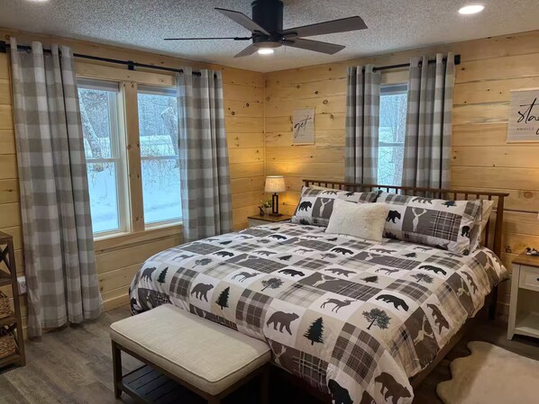 Ein gemütliches Schlafzimmer mit Bett, Sitzbank und Deckenventilator.