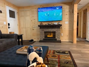 Ein Wohnzimmer mit Kamin, Wand-Fernseher und einer Couch.