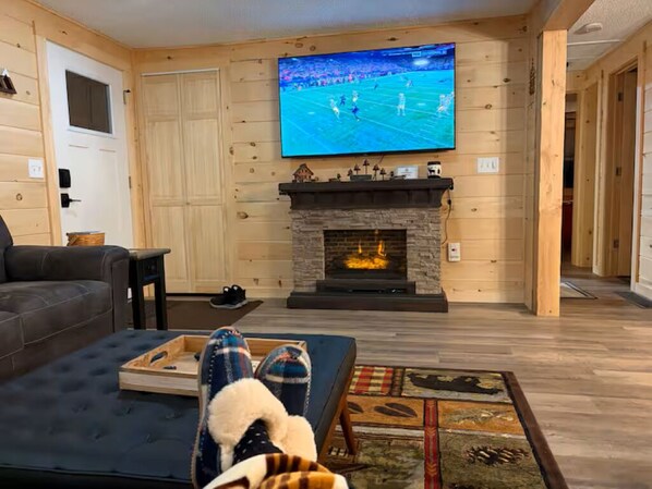 Una sala de estar con chimenea, televisor montado en la pared y un sofá.