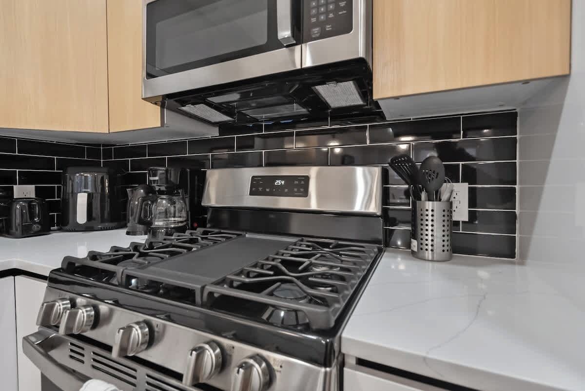 Una cocina con estufa a gas, microondas y cafetera.