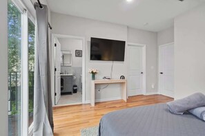 Ein Schlafzimmer mit Bett, Schreibtisch, Fernseher und Blick ins Freie.
