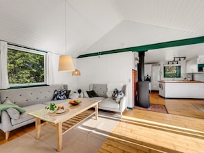 Ein modernes Wohnzimmer mit Sofa, Couchtisch und Blick zur Küche.
