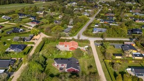 Ett flygbildsfoto av ett bostadsområde med hus, vägar och en vattenyta i bakgrunden.