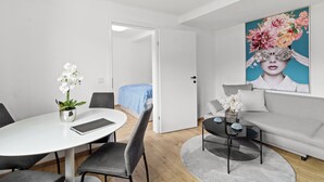 A modern room with a round dining table, grey chairs, a sofa, a coffee table, and a painting on the wall. - FarawayHomes Studios Leoben P74 (Donawitz)