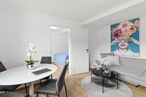 Ein modernes Zimmer mit einem runden Esstisch, grauen Stühlen, einer Couch, einem Couchtisch und einem Bild an der Wand.