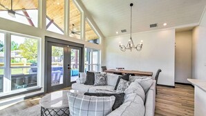 Un salon spacieux avec un grand canapé d’angle, un coin repas et une vue sur l’extérieur grâce à de grandes fenêtres.