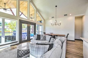 Ein geräumiges Wohnzimmer mit einer großen Eckcouch, einem Essbereich und Blick ins Freie durch große Fenster.