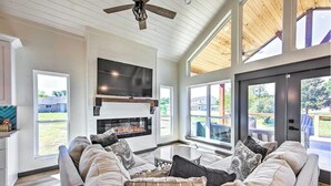 Un salon spacieux doté d’une cheminée, de grandes fenêtres et d’un ventilateur de plafond.