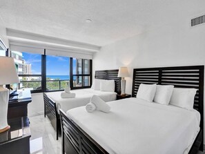 A hotel room with two beds, a desk, and a view of the city. - Spacious Ocean View Condo / Beach Service / 704 (Miami Beach)