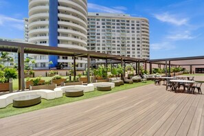 A rooftop deck with outdoor seating and planters, a covered area, and a view of a high-rise building. - Spacious Ocean View Condo / Beach Service / 704 (Miami Beach)