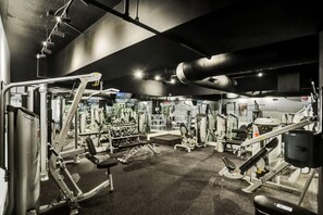 Ein Fitnessstudio mit verschiedenen Trainingsgeräten, Gewichtsstationen und einer Spiegelwand.