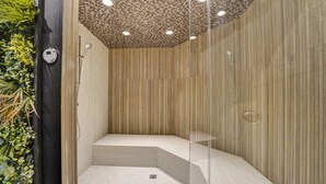 Eine moderne Dusche mit kariertem Deckenverkleidung, vertikaler Holzverkleidung und einer Glasabtrennung.