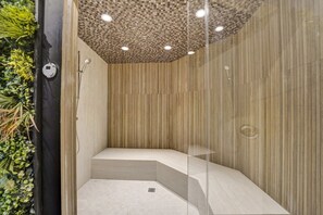 A modern shower with a checkered ceiling, vertical wooden paneling, and a glass partition. - Spacious Ocean View Condo / Beach Service / 704 (Miami Beach)