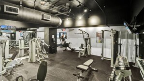 Ein Fitnessraum mit verschiedenen Trainingsgeräten, Laufbändern und einer Bank.