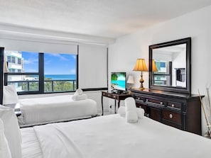 A hotel room with two beds, a TV, a lamp, a mirror, and a view of the ocean. - Spacious Ocean View Condo / Beach Service / 704 (Miami Beach)