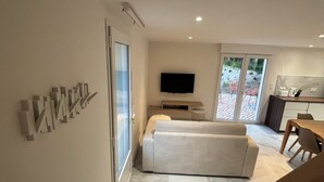 Ein modernes Wohnzimmer mit einer Couch, einem Flachbildfernseher und einem Essbereich mit Tisch und Stühlen.
