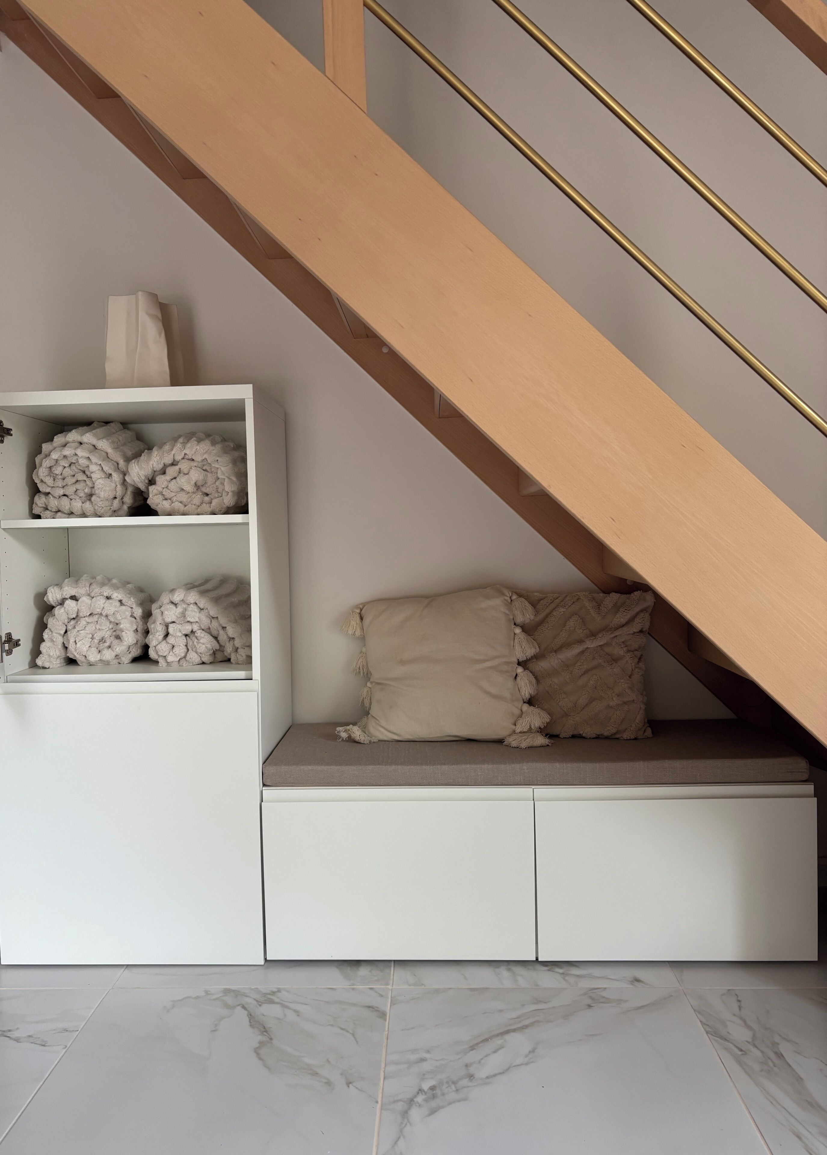 A staircase with wooden steps and a beige cushion on a white bench.